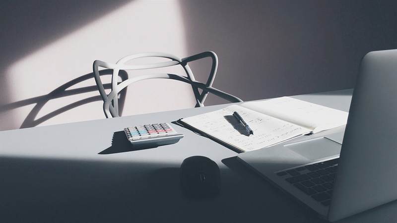 Desk with a calculator, notebook, and laptop